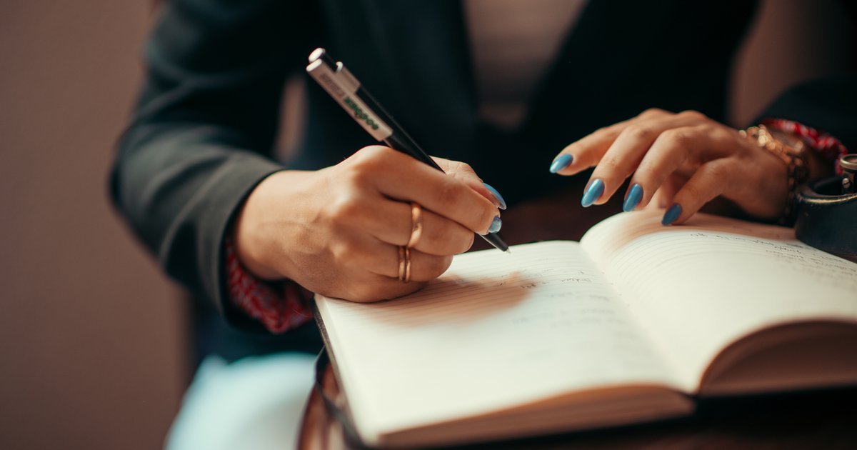 Businesswoman writing in a notebook, illustrating high-quality business writing and editing workflows